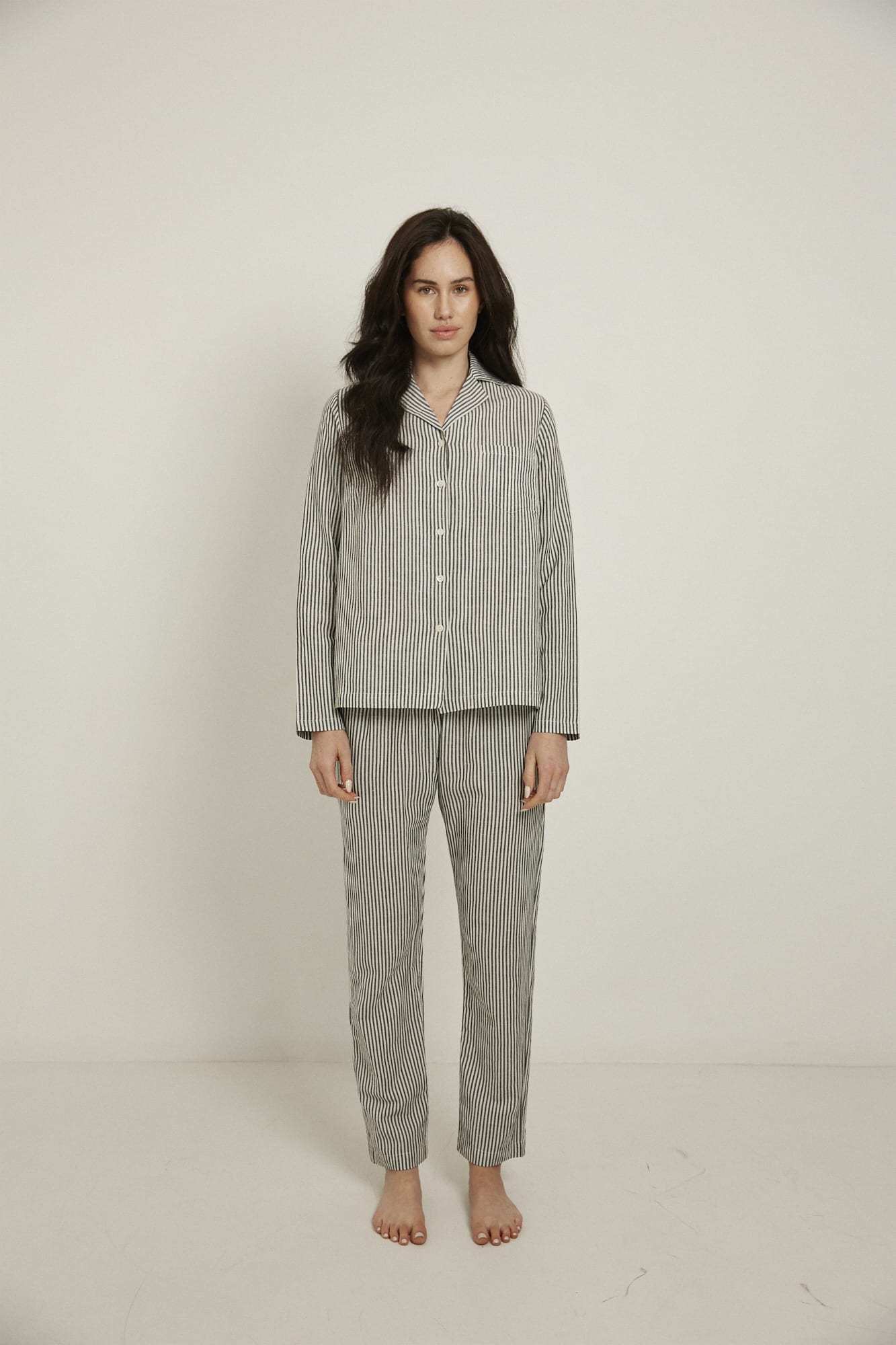 Women’s pyjama set including a long sleeve shirt and long sleeve pants. Made from an organic cotton and linen blend, in a black and white stripe.  The shirt has shell buttons, a front pocket and a back pleat.  The pants feature an elasticated waistband for comfort.