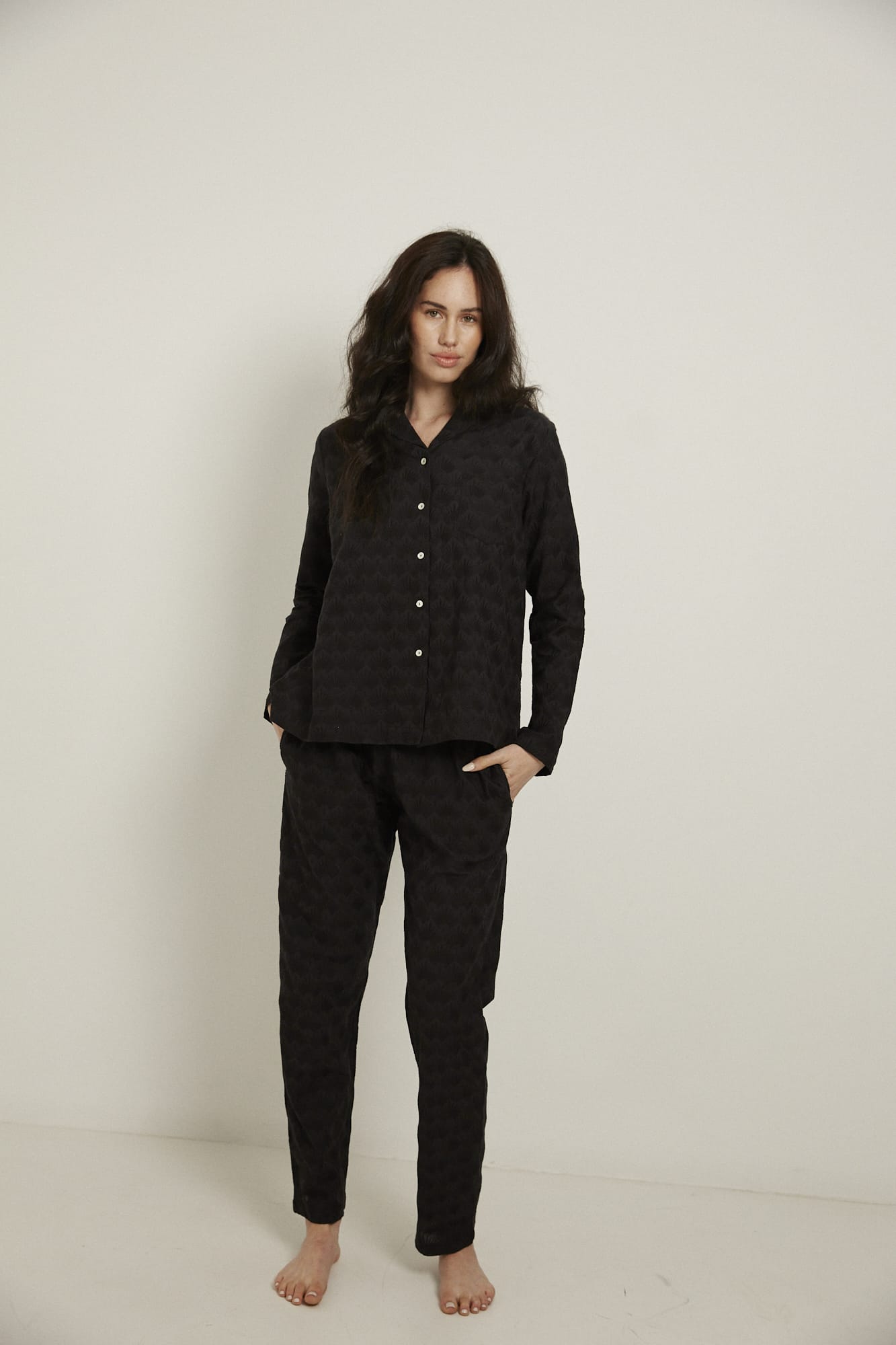 Women’s pyjama set including a long sleeve shirt and long sleeve pants. Made from 100% organic cotton, in black colour featuring delicate all over embroidery. The shirt has shell buttons, a front pocket and a back pleat.  The pants feature an elasticated waistband for comfort.