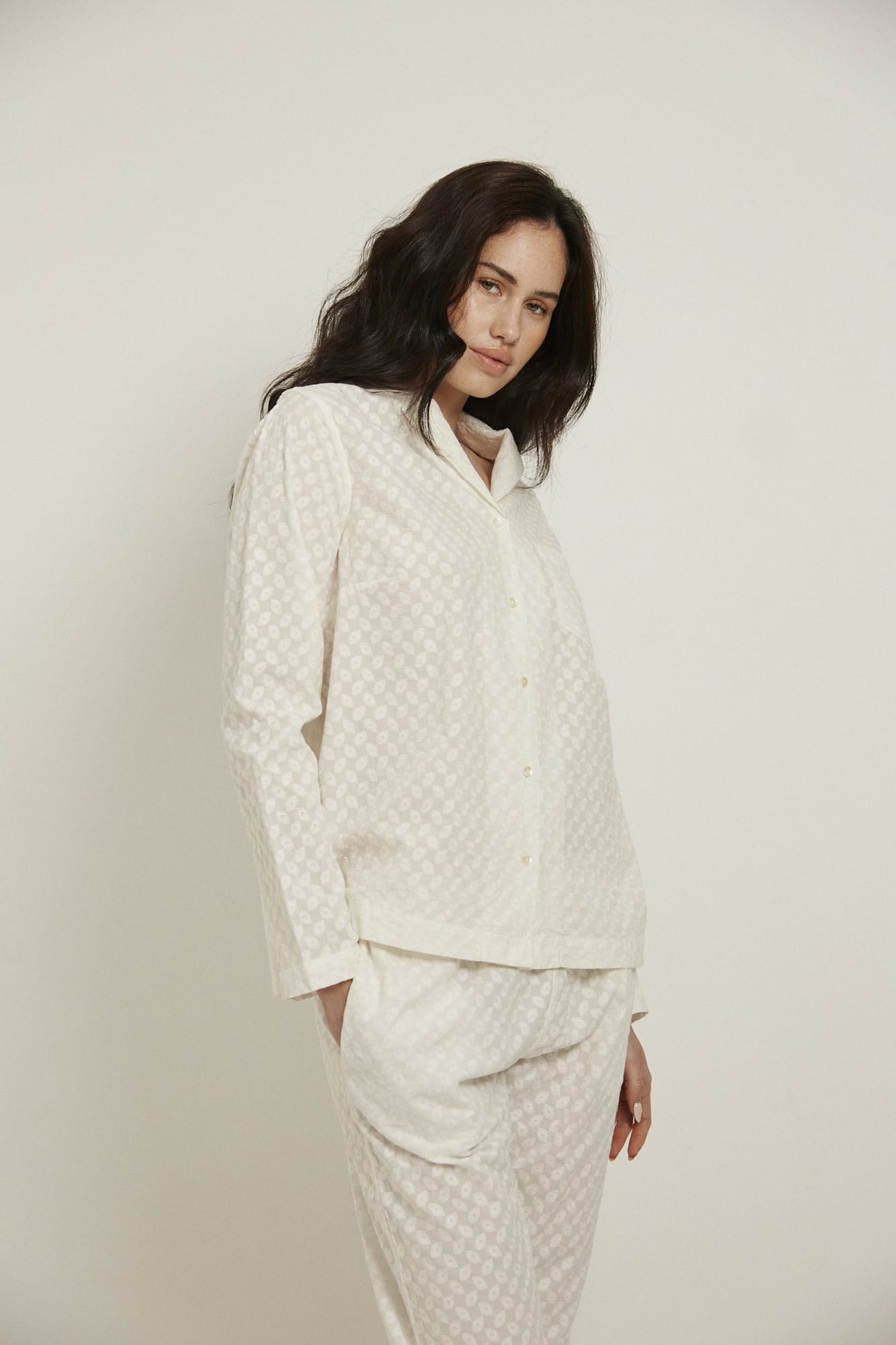 Women’s pyjama set including a long sleeve shirt and long sleeve pants. Made from 100% organic cotton, in white colour featuring delicate all over embroidery. The shirt has natural shell buttons, a front pocket and a back pleat.  The pants feature an elasticated waistband for comfort.  