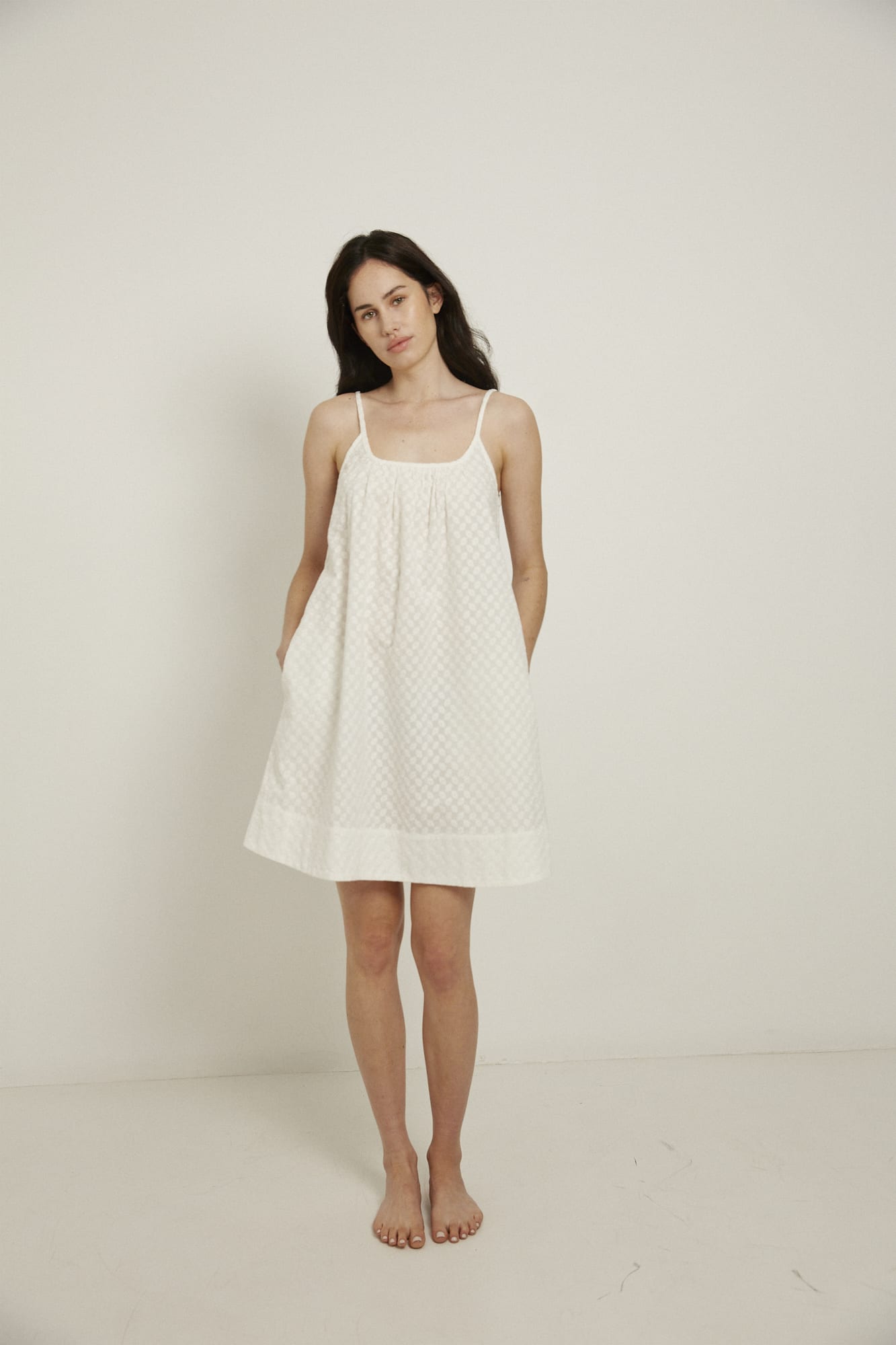 This knee length women’s nightdress dress features a scoop neck, adjustable spaghetti straps and side pockets. Finished with a wide hem, French seams, it is made from 100% organic cotton, in white, and features delicate all over embroidery.