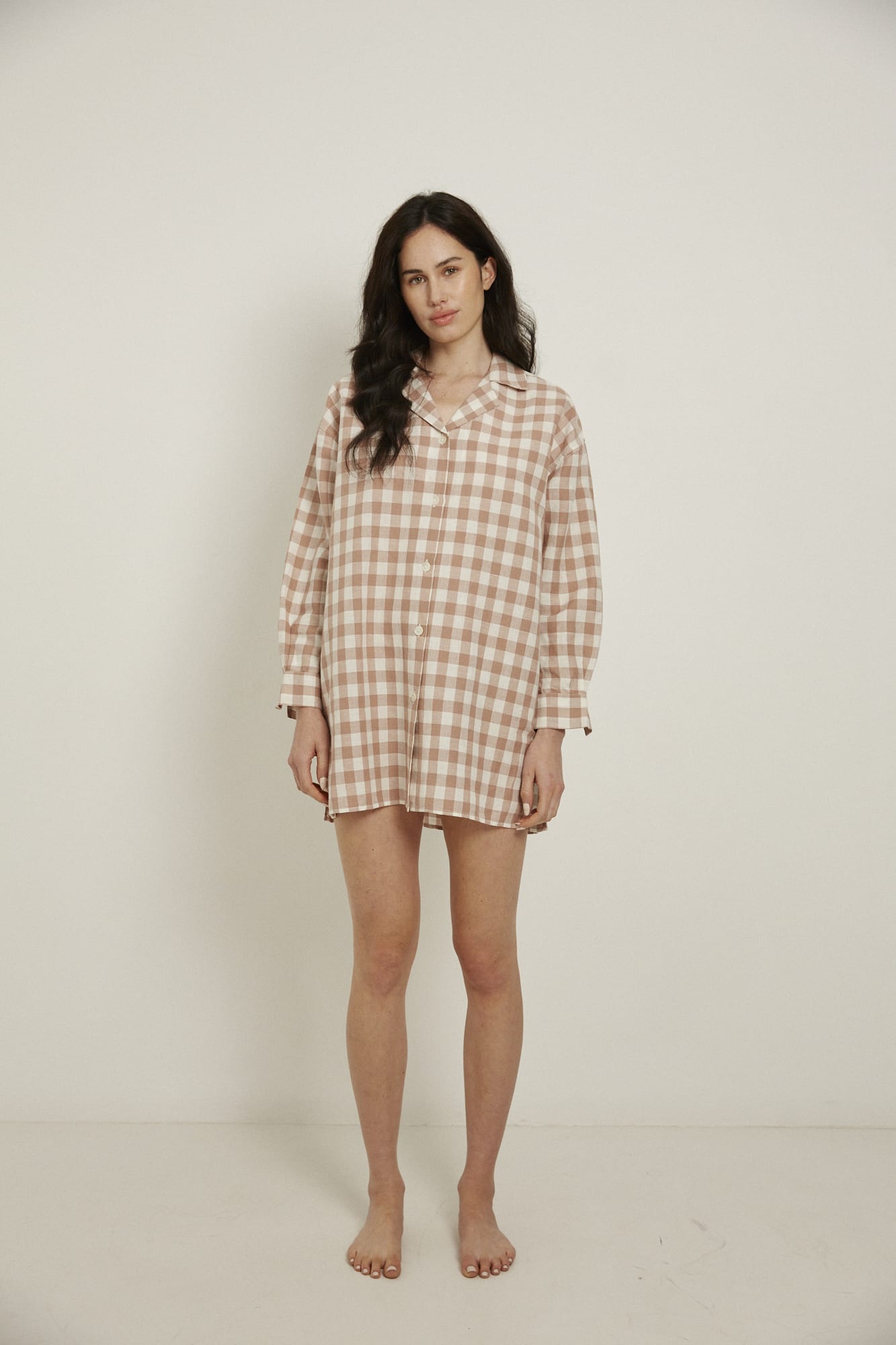 This knee length women’s nightdress dress has a boxy shape, with a comfortable dropped shoulder, and natural shell buttoned cuffs and placket.  Made from an organic cotton and linen blend, in a pink and white check, this nightshirt features a single breast pocket, back box pleat and locker loop detail, and is finished with French seams. 