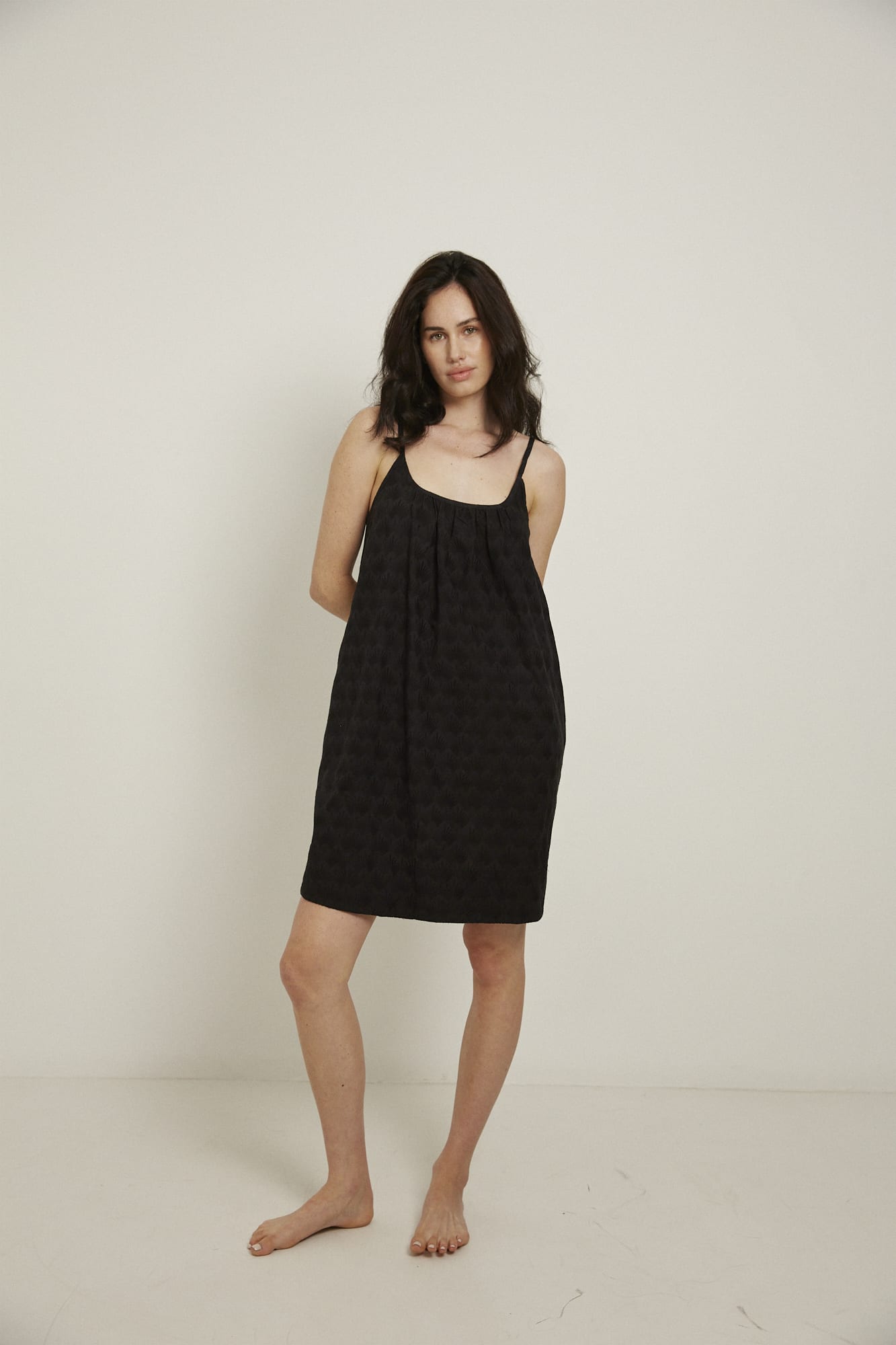 This knee length women’s nightdress dress features a scoop neck, adjustable spaghetti straps and side pockets. Finished with a wide hem, French seams, it is made from 100% organic cotton, in black, and features delicate all over embroidery.
