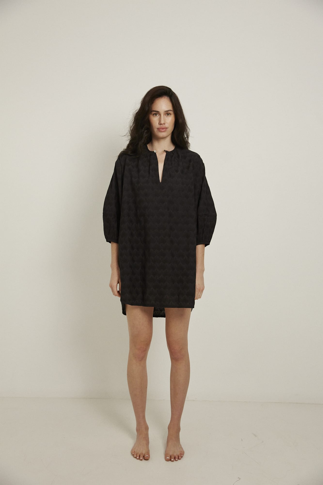 This knee length women’s nightdress dress has a relaxed fit with gathered sleeves ,and a single loop buttoned neckline which opens to a V-neck. In black and made from 100% organic cotton, it features delicate all over embroidery, deep pockets, and is finished with French seams.
