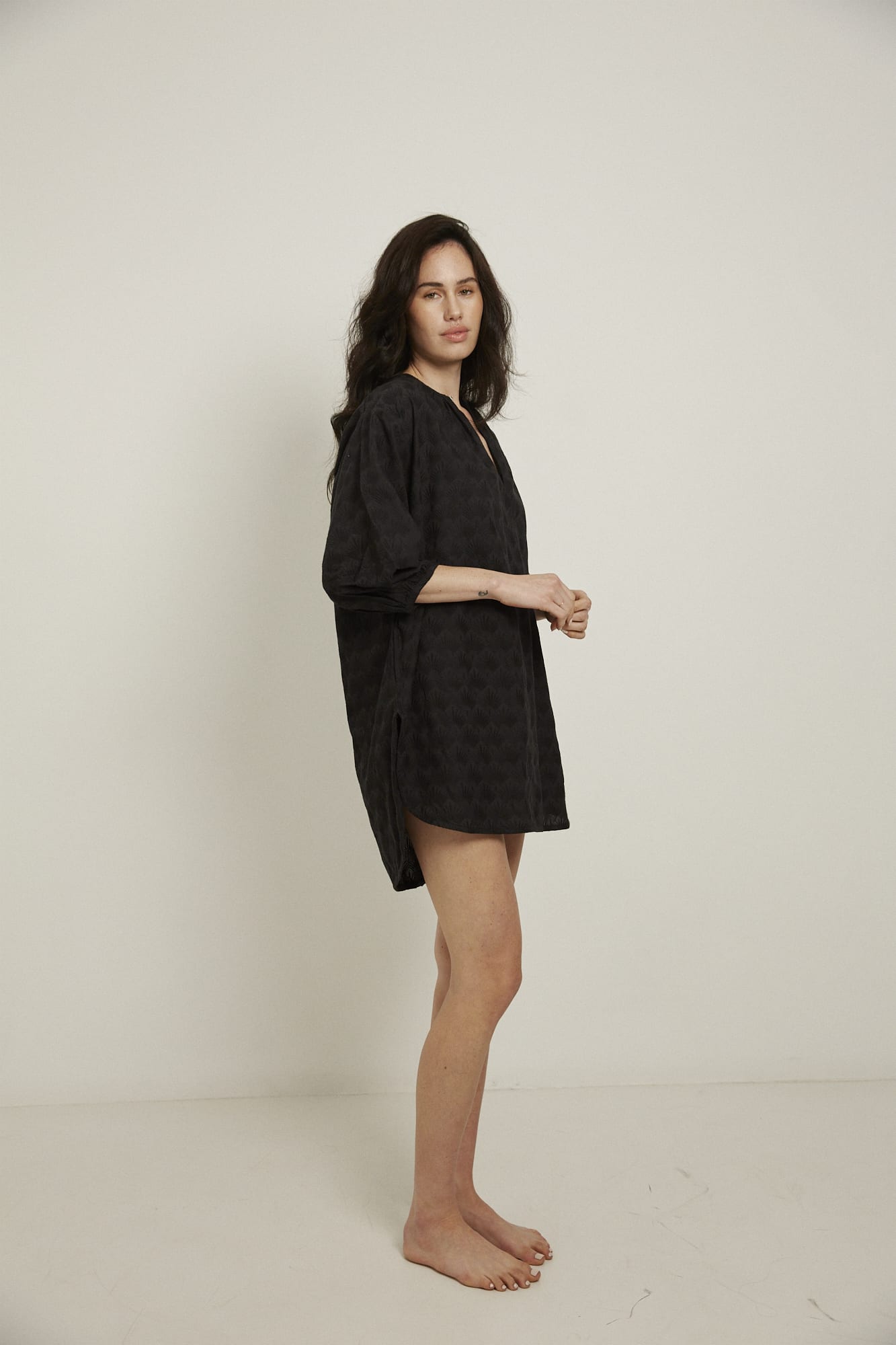 This knee length women’s nightdress dress has a relaxed fit with gathered sleeves ,and a single loop buttoned neckline which opens to a V-neck. In black and made from 100% organic cotton, it features delicate all over embroidery, deep pockets, and is finished with French seams.