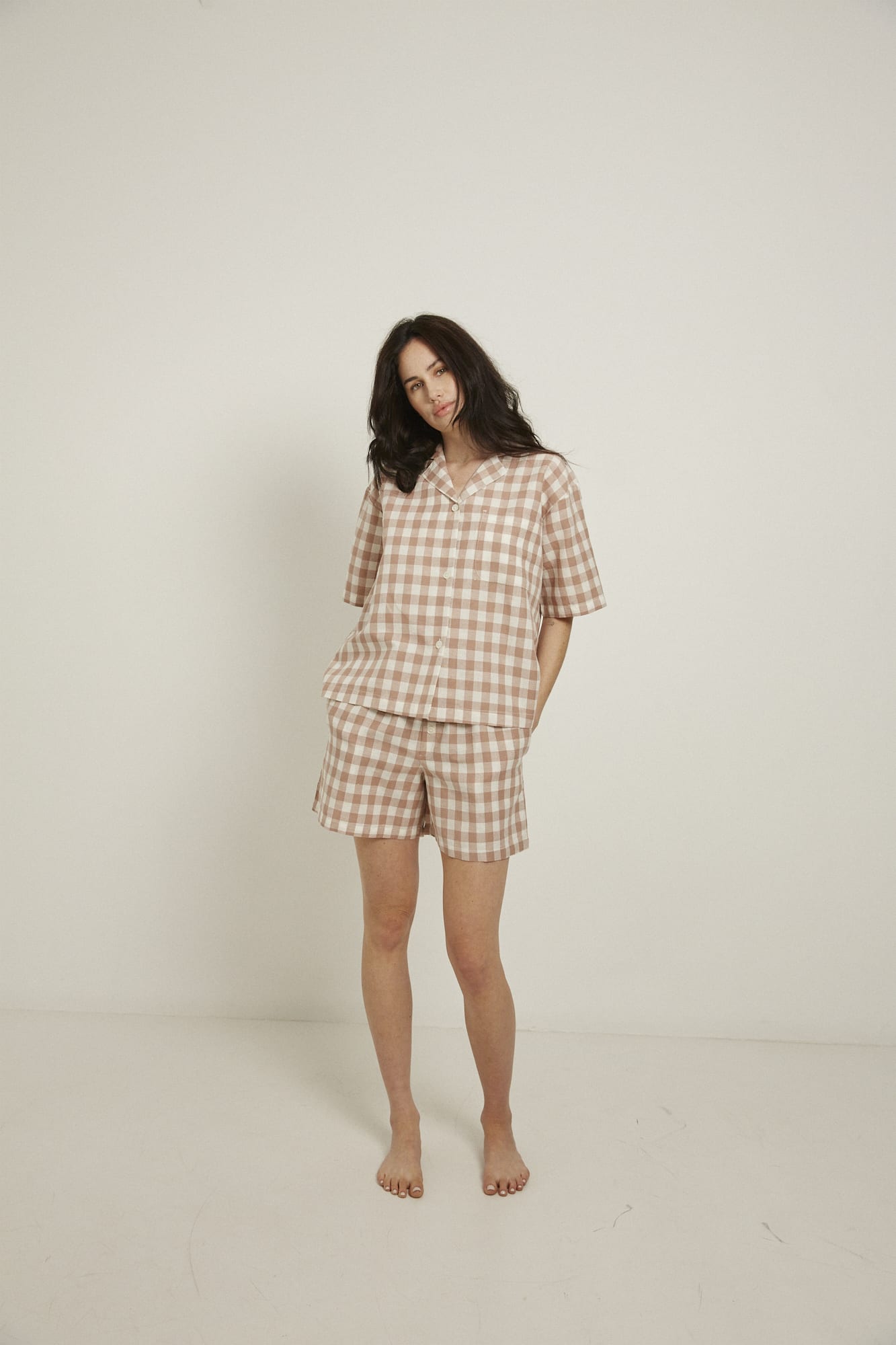 Women’s pyjama set including a short sleeve shirt and shorts. Made from an organic cotton and linen blend, in a pink and white check.  The shirt has shell buttons, a front pocket and a back pleat with locker loop detail.  The shorts feature natural shell buttons and an elasticated waistband for comfort.