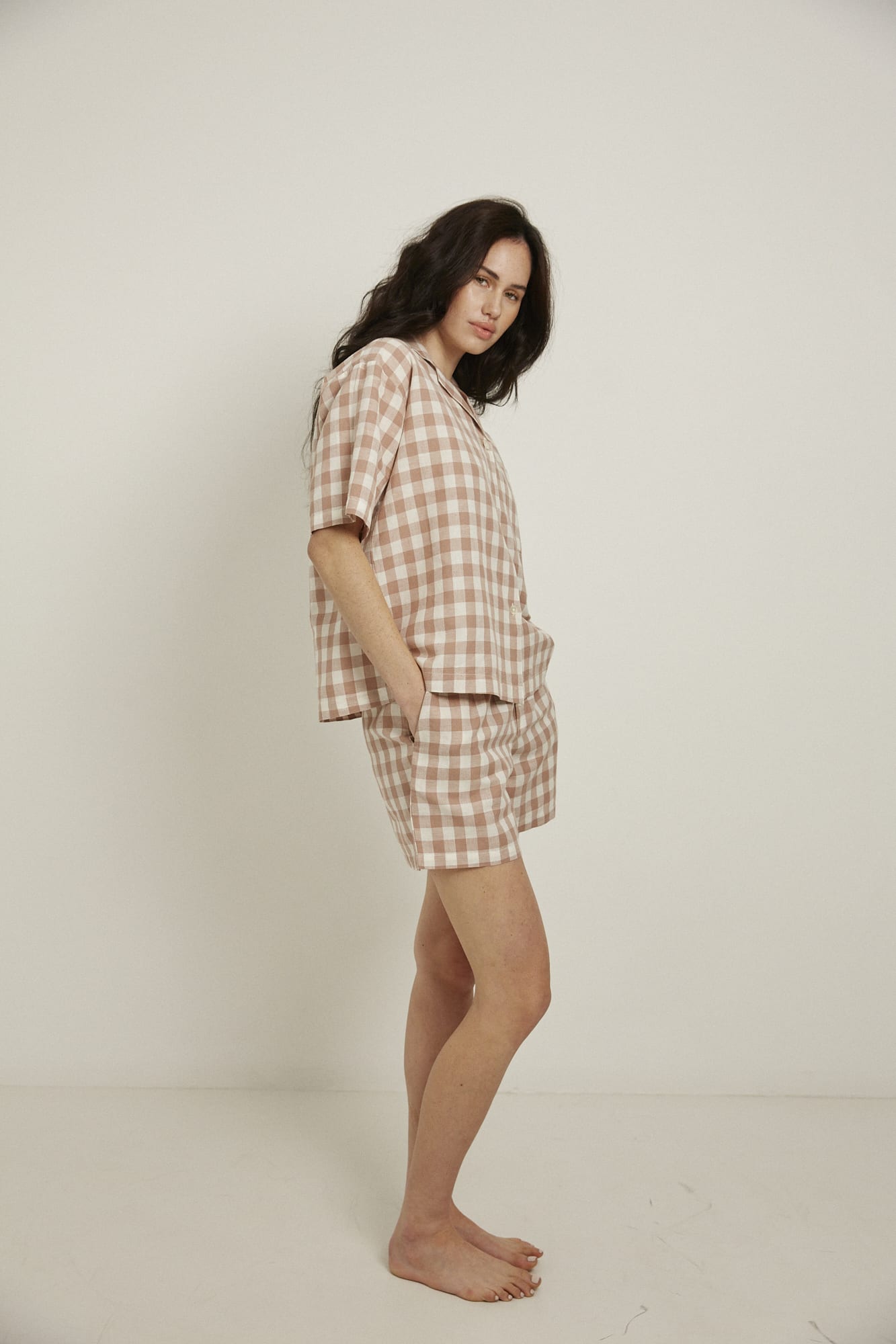 Women’s pyjama set including a short sleeve shirt and shorts. Made from an organic cotton and linen blend, in a pink and white check.  The shirt has shell buttons, a front pocket and a back pleat with locker loop detail.  The shorts feature natural shell buttons and an elasticated waistband for comfort.