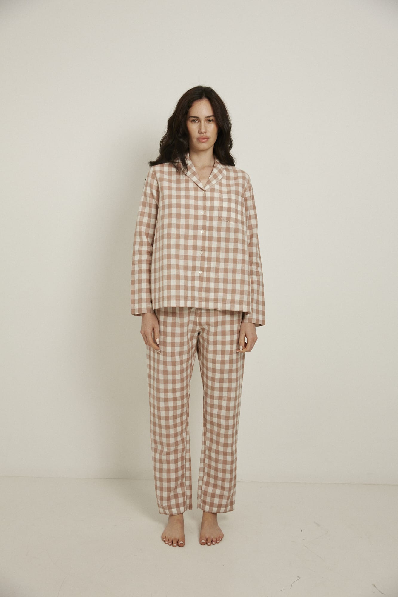 Women’s pyjama set including a long sleeve shirt and long sleeve pants. Made from an organic cotton and linen blend, in a pink and white check.  The shirt has shell buttons, a front pocket and a back pleat.  The pants feature an elasticated waistband for comfort.