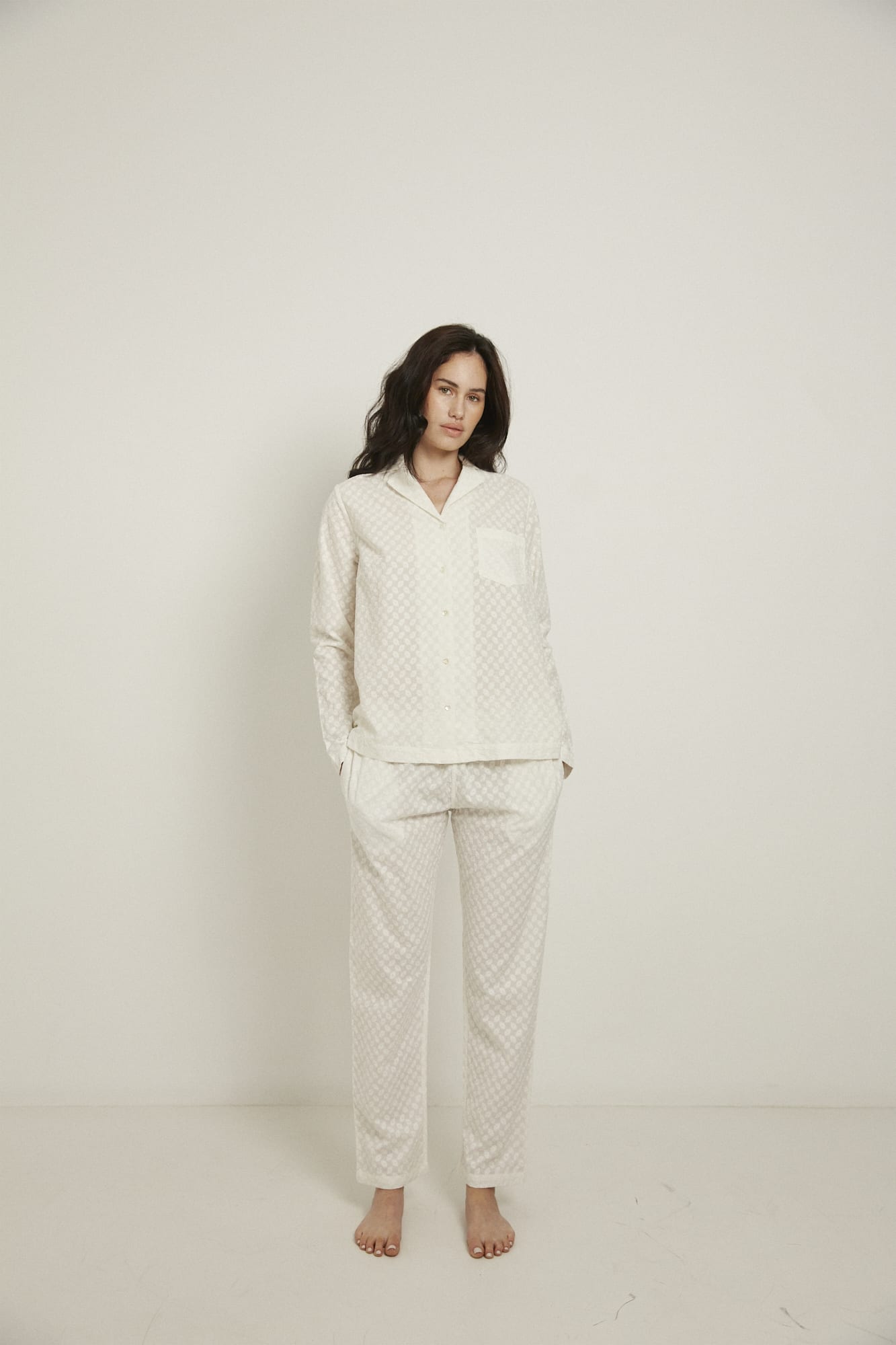 Women’s pyjama set including a long sleeve shirt and long sleeve pants. Made from 100% organic cotton, in white colour featuring delicate all over embroidery. The shirt has natural shell buttons, a front pocket and a back pleat.  The pants feature an elasticated waistband for comfort.  