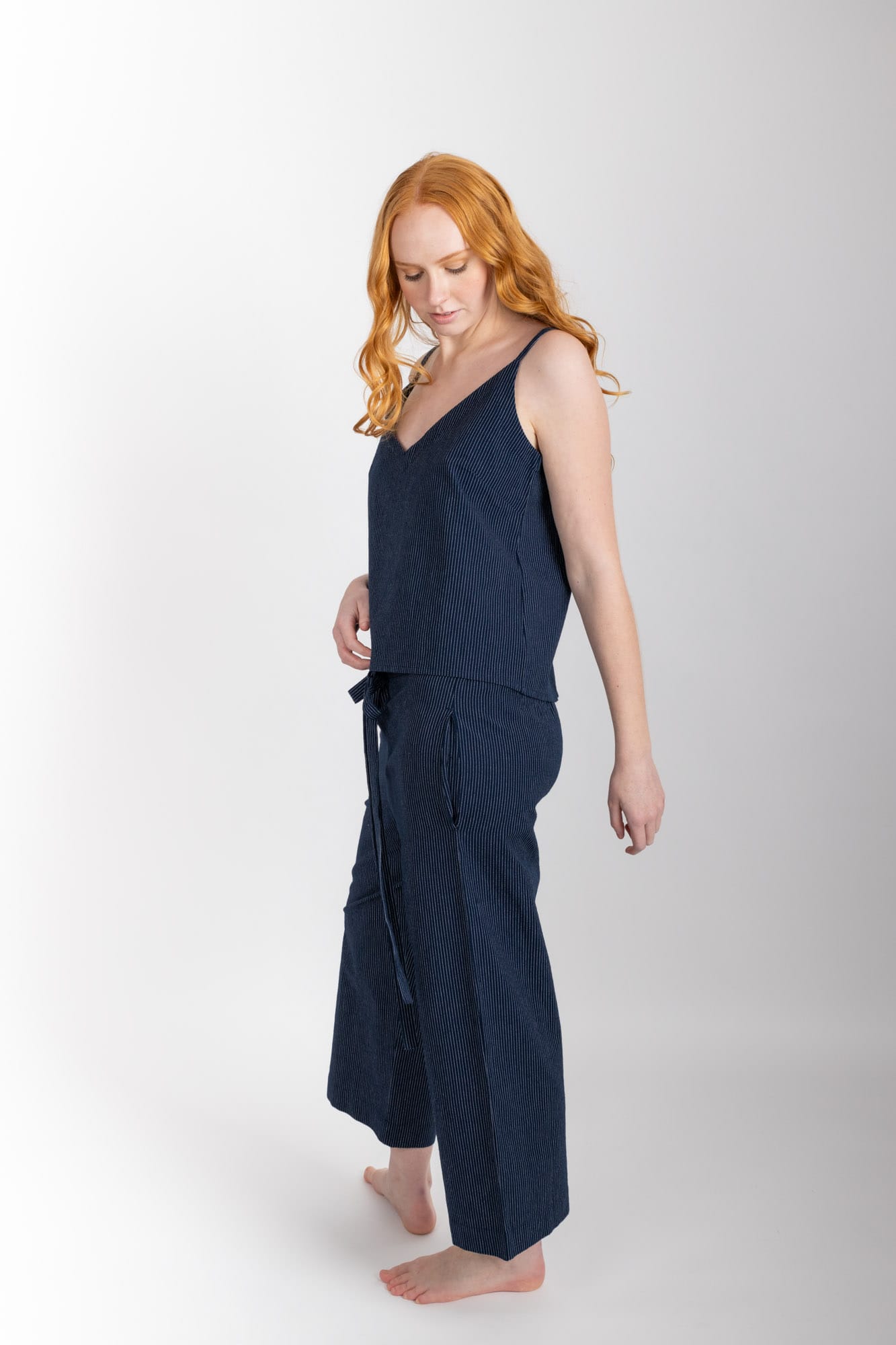 Women’s sleepwear set featuring a V-neck, swing-style camisole with adjustable straps. Paired with straight-leg cropped pant with an elasticated waist, flat front, and drawstring detail, these pants are comfortable and flattering. Woven in 100% organic cotton, both pieces have been finished with French seams.