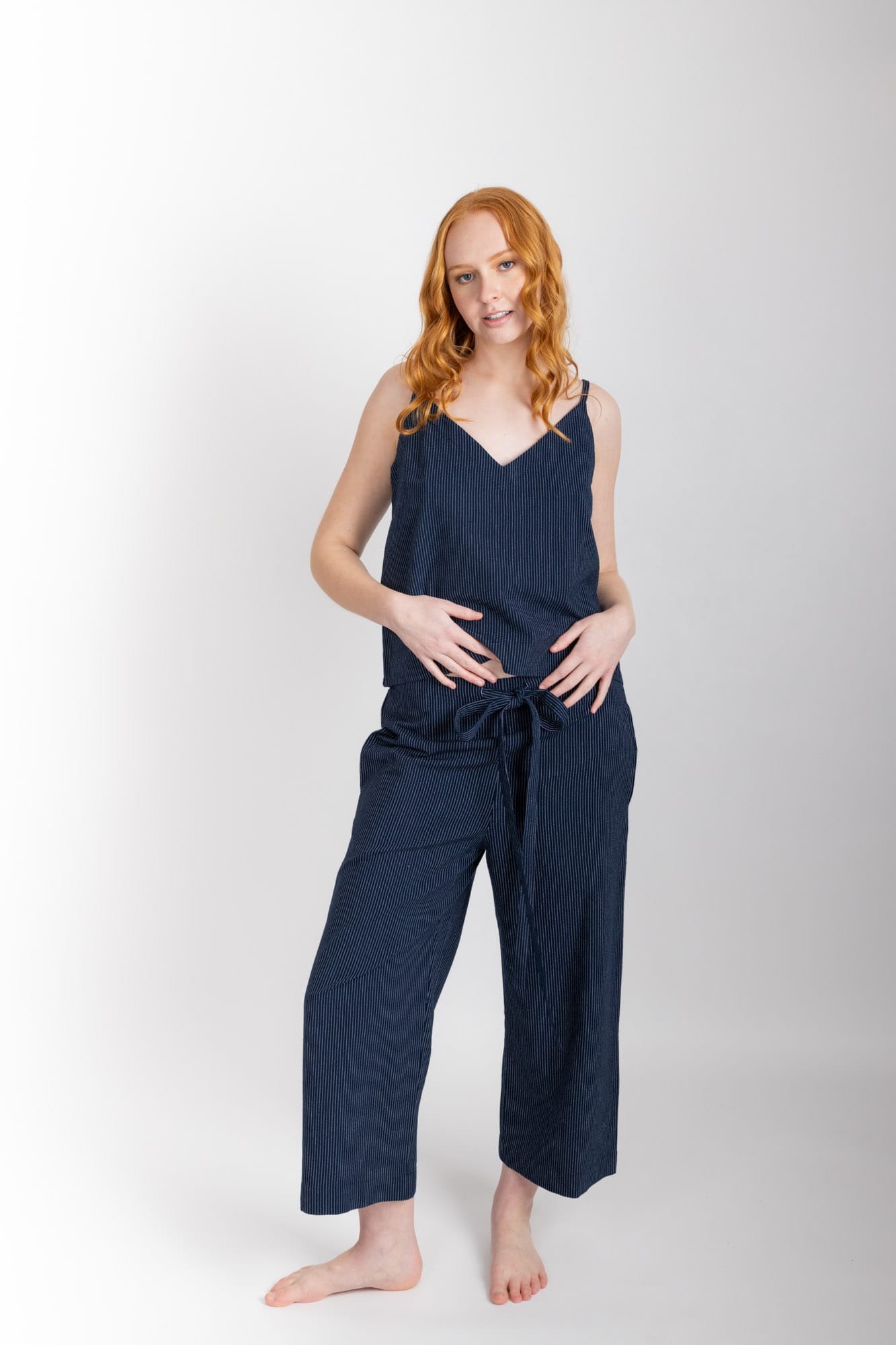 Women’s sleepwear set featuring a V-neck, swing-style camisole with adjustable straps. Paired with straight-leg cropped pant with an elasticated waist, flat front, and drawstring detail, these pants are comfortable and flattering. Woven in 100% organic cotton, both pieces have been finished with French seams.