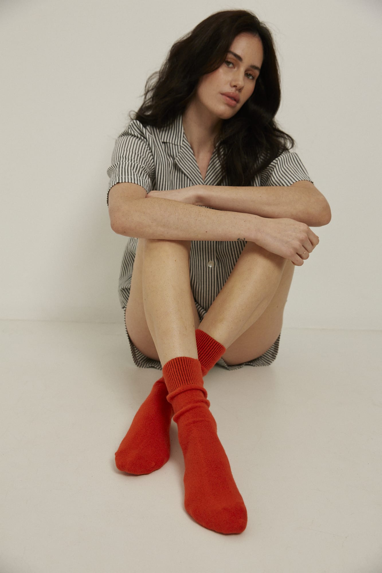 Woman wearing Perino bed socks in colour Orange, and Black and White Striped sleepwear.  Both items from General Sleep.  
